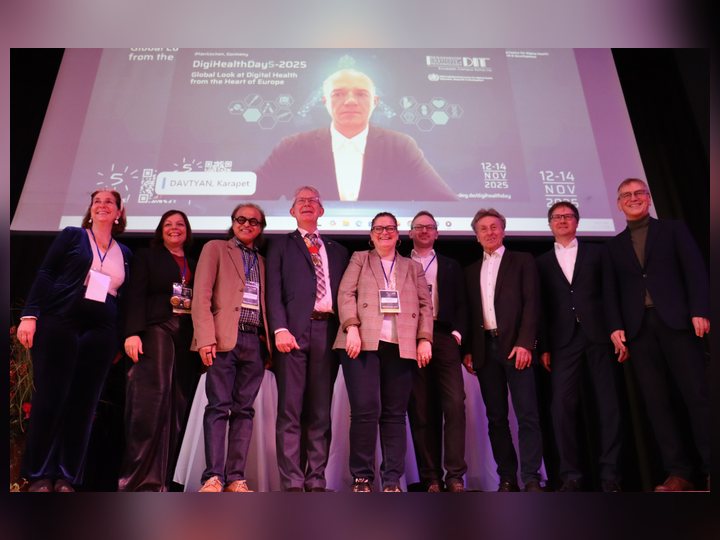 A remote colleague appearing on screen with international conference guests
